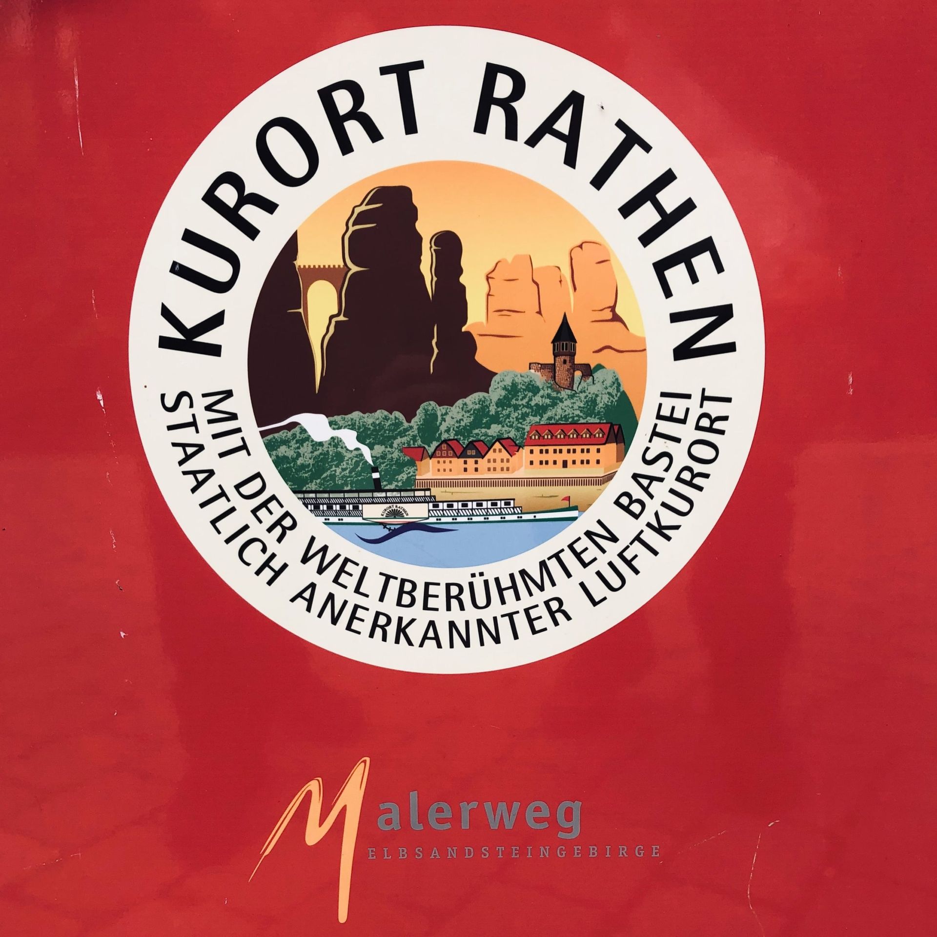 Emblem des Kurorts Rathen und des Malerwegs auf roter Wand